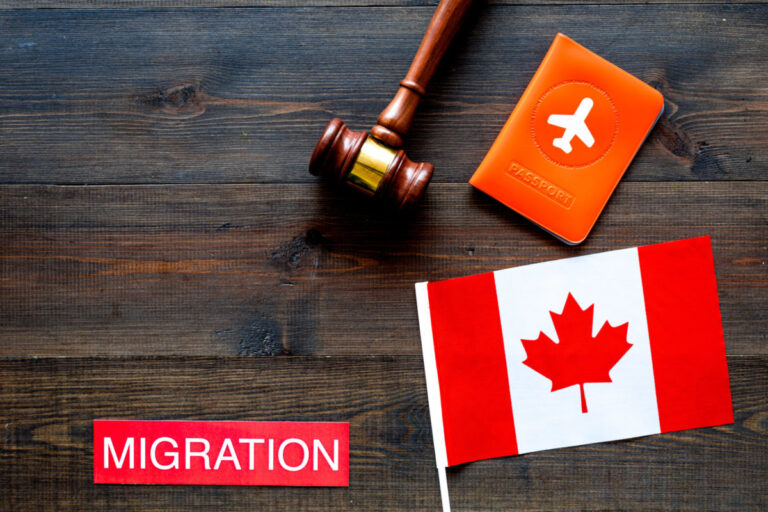 Immigration to Canada concept. Text immigration near passport cover and canadian flag, hammer on dark wooden background top view space for text